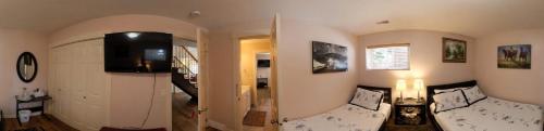 a living room with a couch and a tv on the wall at Rodee Homestay in West Kelowna