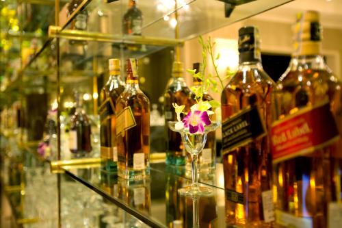 a glass shelf with bottles of wine and a flower in a glass at Eldora Hotel in Hue