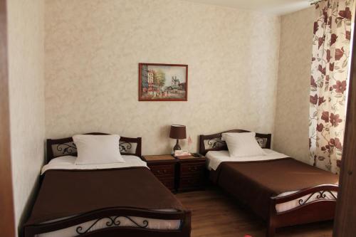 a bedroom with two beds and a table with a lamp at Mini-Hotel Razgulyay in Ryazan