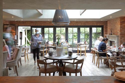 a person walking through a restaurant with tables and chairs at No38 The Park in Cheltenham