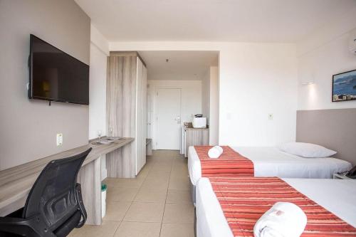 a hotel room with two beds and a flat screen tv at Flat 905 - Localização privilegiada em Macaé in Macaé