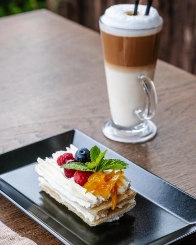 a piece of cake with fruit on a plate next to a drink at Globus Hotel in Ternopilʼ