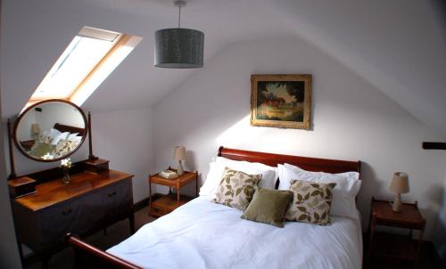 a bedroom with a bed with a mirror and a window at Orchard Barn, Woodhayes in Honiton