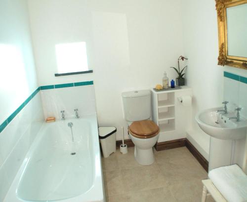 a bathroom with a tub and a toilet and a sink at Orchard Barn, Woodhayes in Honiton