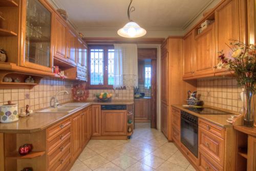 una cocina con armarios de madera y fregadero en Villa Elena Crete, en Viranepiskopí