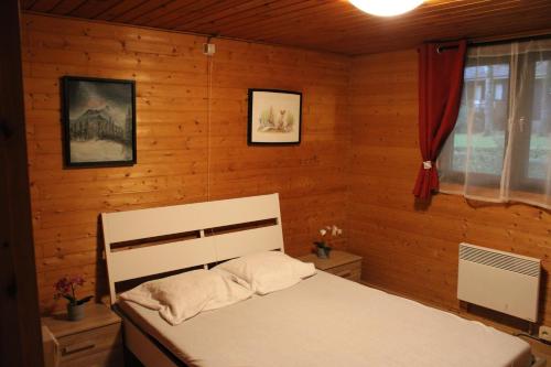 a bedroom with a white bed in a wooden wall at Chalet Ardennais 240 - La Boverie - Rendeux in Rendeux