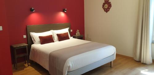a bedroom with a large bed with a red wall at Château de Grandmont Chambres d'hôtes in Blacé
