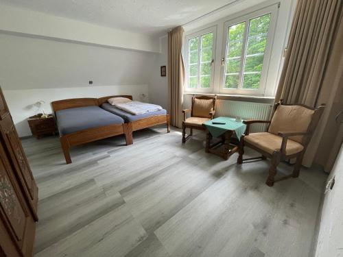 a bedroom with a bed and two chairs and a table at Hotel & Gastropark Loemühle in Marl