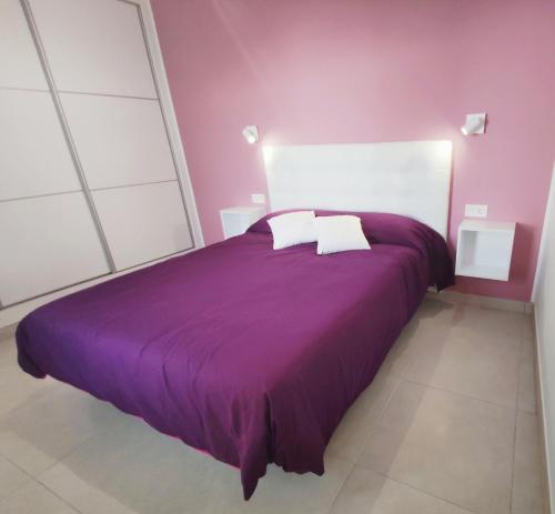 - un lit violet avec 2 oreillers au-dessus dans l'établissement Apartamento Vero Senator, Costa Teguise, à Costa Teguise