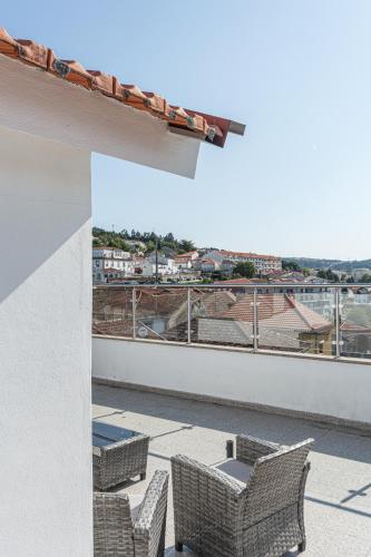 a balcony with chairs and a view of a city at Isabel do Couto - casa de charme in Castro Daire