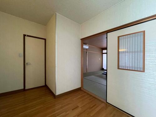 ein leeres Zimmer mit einer Tür zu einem Schlafzimmer in der Unterkunft Iso Tokei - Vacation STAY 61860v in Kanayama
