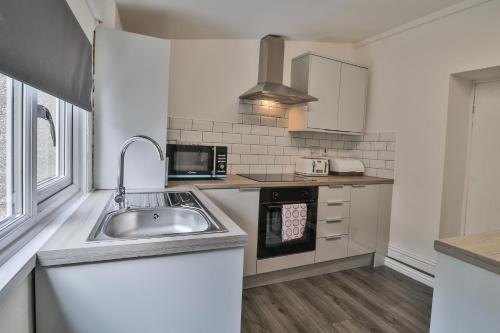 a kitchen with a sink and a microwave at Cozy Cribs near Zipworld, Dare Valley Bike Park, Pen-y-fan & Four Waterfalls Walk in Aberdare