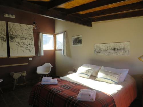 a bedroom with a bed and a chair and a window at CasaEstudio in El Chalten