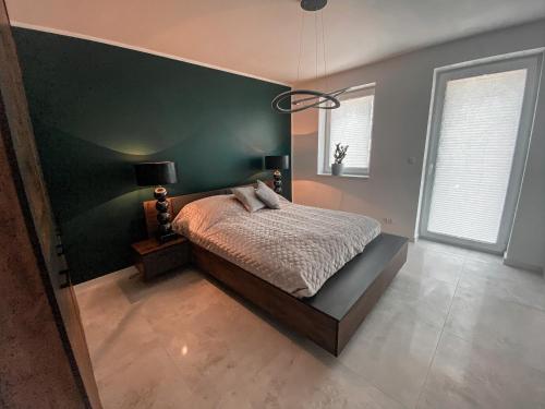 - une chambre avec un lit et un mur vert dans l'établissement NADJEZIORNA LUX 2, à Ełk