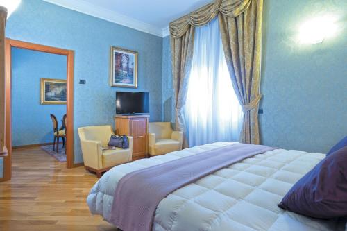 ein Schlafzimmer mit einem Bett und ein Zimmer mit einem TV in der Unterkunft Ele Green Park Hotel Pamphili in Rom