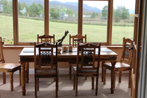 a dining room table with four chairs and a large window at Ach-Na-Sidhe in Dores
