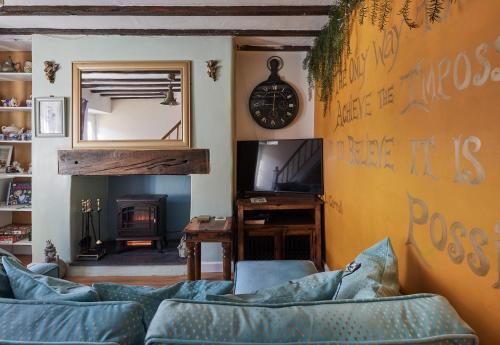 a living room with a couch and a clock on the wall at Violets Wonderland Cottage in Llandudno