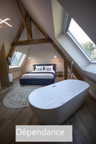 a bathroom with a bath tub and a bed at Château de la Bribourdière in Putot-en-Auge