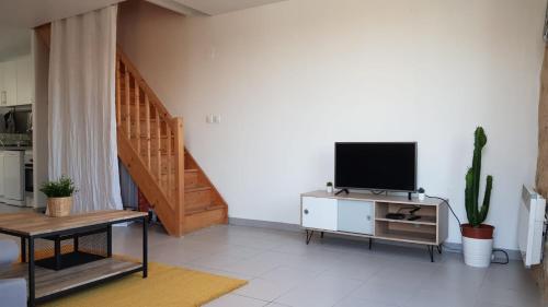 a living room with a television and a staircase at Nathan Home in Saint-Jean-de-Blaignac