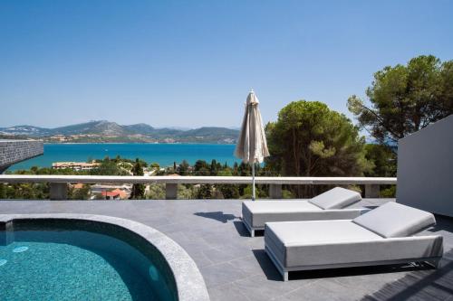 a patio with a swimming pool and an umbrella at Ionian Grand Villas - Villa Estella in Lygia