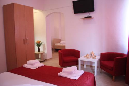 a room with two chairs and a bed and a tv at Hotel Sir Gara de Nord in Bucharest