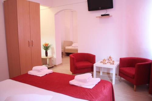 a room with two red chairs and a bed and a table at Hotel Sir Gara de Nord in Bucharest