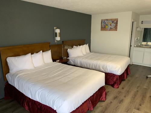 two beds in a hotel room with white sheets at Rodeway Inn Augusta North Washington Road in Augusta