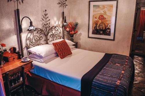 a bedroom with a bed and a table and a picture at Meson Panza Verde in Antigua Guatemala