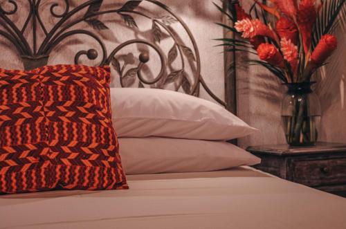 a bed with a vase with flowers in a room at Meson Panza Verde in Antigua Guatemala