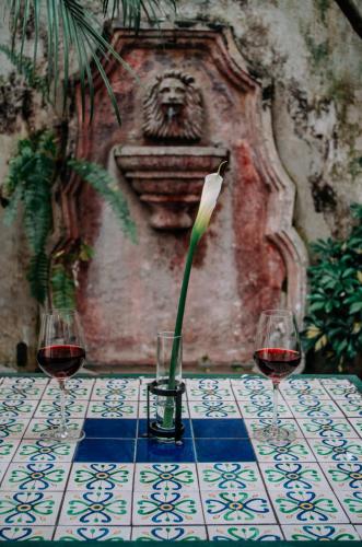 two glasses of wine and a flower in a vase on a table at Meson Panza Verde in Antigua Guatemala