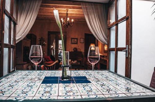 a table with three wine glasses and a vase on it at Meson Panza Verde in Antigua Guatemala