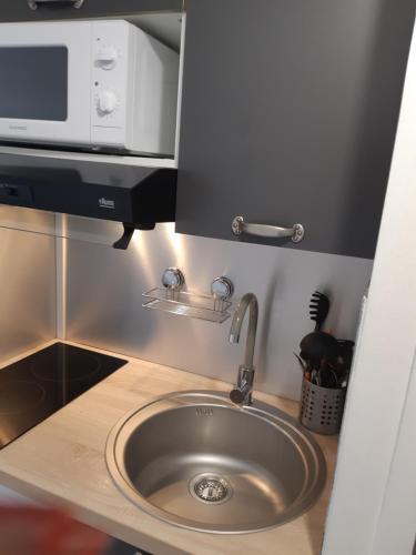 eine Küche mit einer Spüle und einer Mikrowelle in der Unterkunft Bonheur à la résidence Savane in Le Gosier