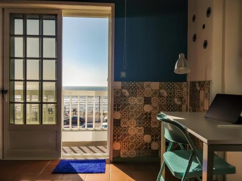 a door leading to a balcony with a table and chair at Brisa do Mar da Vagueira in Praia da Vagueira