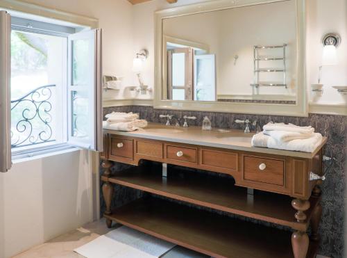 une salle de bain avec un lavabo et un miroir dans l'établissement Villa Pivoine - Château La Martinette, à Lorgues