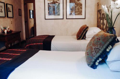 two beds in a hotel room with white sheets at Meson Panza Verde in Antigua Guatemala
