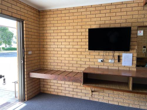 a brick wall with a flat screen tv on a wall at Lakeview Motel in Yarrawonga