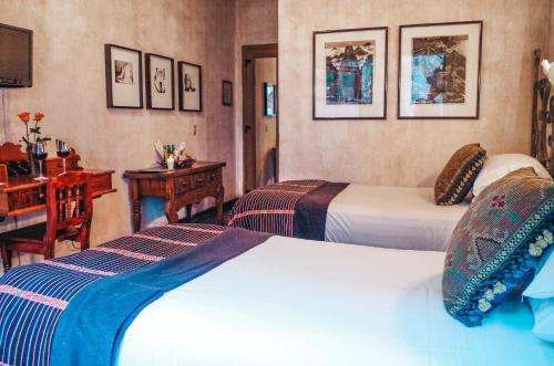 a hotel room with two beds and a desk at Meson Panza Verde in Antigua Guatemala
