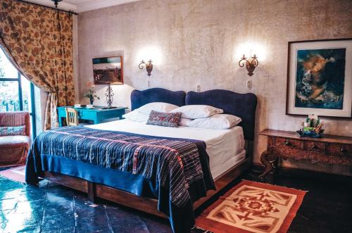 a bedroom with a large bed with a blue headboard at Meson Panza Verde in Antigua Guatemala