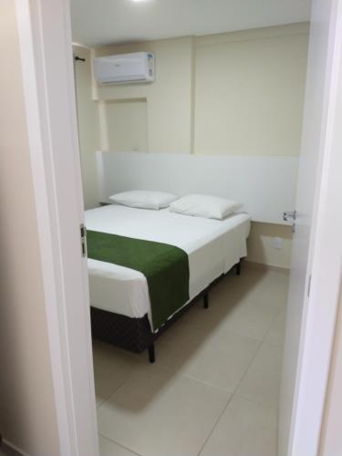 a bedroom with a bed with a green blanket at Pousada Bella Bombinhas - Pé na areia in Bombinhas