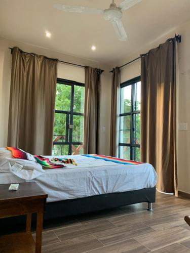 a bedroom with a large bed with windows at Casa Delfín Tulum in Macario Gomez