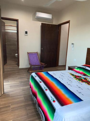 a rainbow colored bed in a room with a chair at Casa Delfín Tulum in Macario Gomez