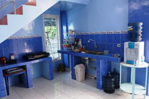 a blue kitchen with a sink and a refrigerator at Kenari Residence in Pekanbaru