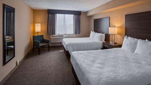 a hotel room with two beds and a chair at Best Western East Towne Suites in Madison