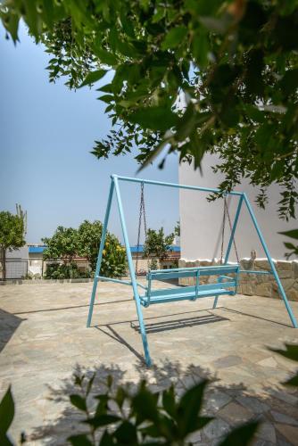 a blue swing in a park with the ocean in the background at Belvedere Village in Agia Pelagia