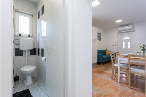 a bathroom with a toilet and a dining room at Apartment Maestral in Mlini