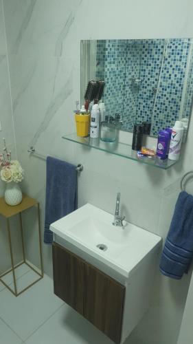 W łazience znajduje się umywalka, lustro i niebieskie ręczniki. w obiekcie Copacabana Av princesa isabel y atlantica w mieście Rio de Janeiro