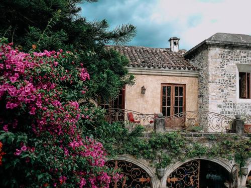 a stone house with pink flowers in front of it at Meson Panza Verde in Antigua Guatemala
