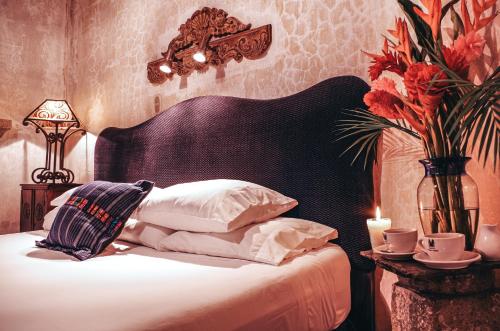 a bed with a black headboard and a table with a candle at Meson Panza Verde in Antigua Guatemala
