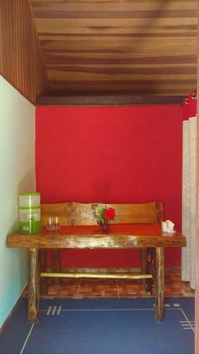 a wooden bench in a room with a red wall at Chalés pouso do vale in Visconde De Maua