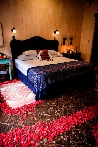 a bedroom with a bed with red flowers on the floor at Meson Panza Verde in Antigua Guatemala